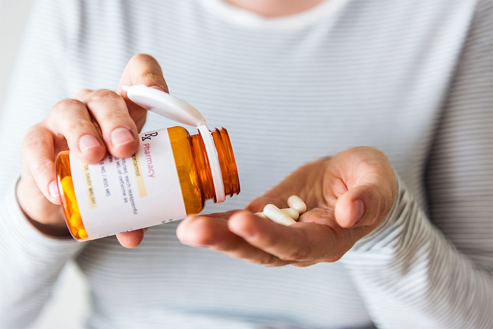 close up of persons hands with pill bottle and pills