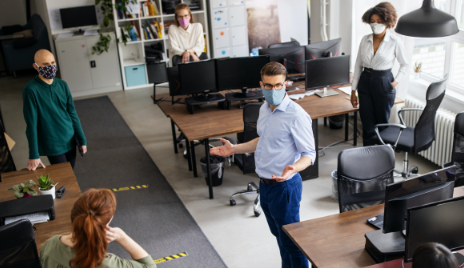 man addresses employees wearing masks in office