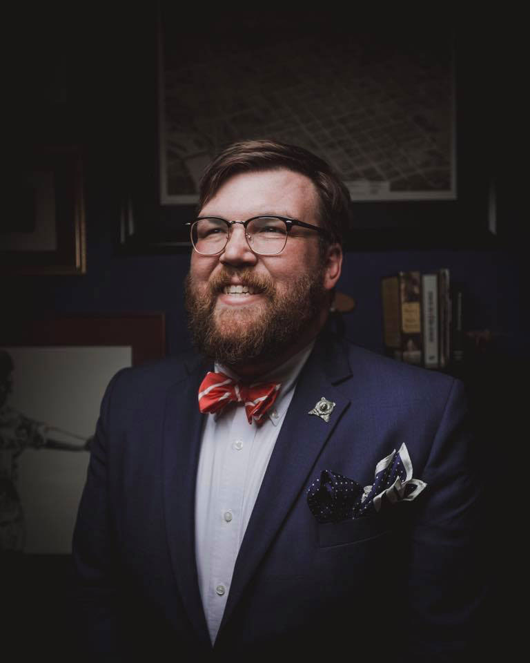 John Tjaarda in a suit smiling at camera